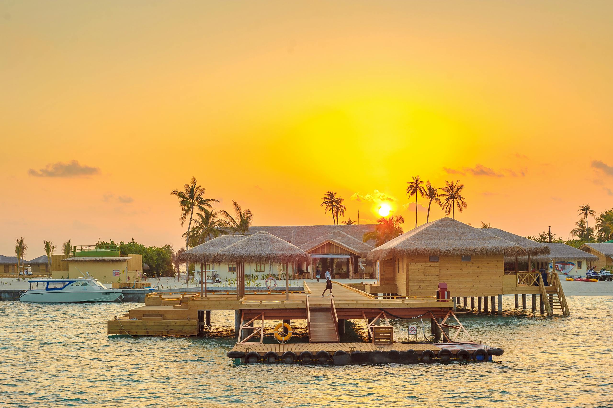 Beautiful sunset view at Kanuhura, Maldives with overwater bungalows and serene ocean surroundings.